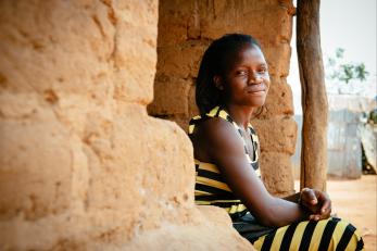 Woman sitting on stoop, smiling, wearing black and yellow striped dress