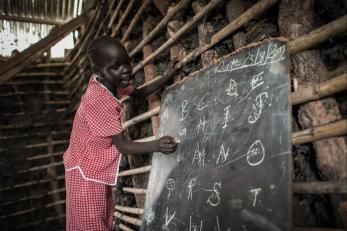 A student in south sudan writing on a chalkboard