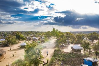 Huts and trees under a blue sky with scattered clouds