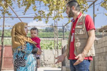 Mercy corps employee talking to maram as she holds her baby