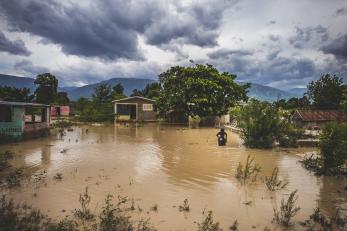 Flooded open area in haiti with a person standing off to the right in the water