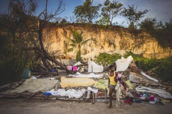 Woman gathering items in front of destroyed home