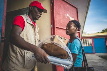 Man handing woman an aid package in haiti