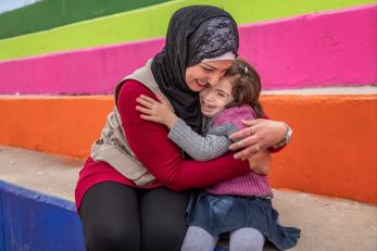 Woman and girl hugging in front of colorful steps