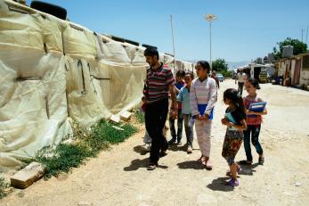 A group of children carrying notebooks and following ziad