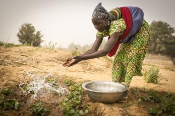 Niger woman scooping water from a bowl