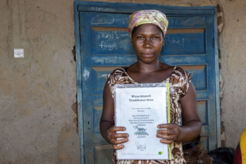 A person holds a document while standing in front of a blue wooden door.