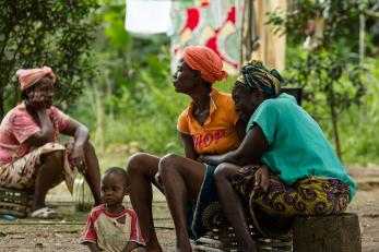 A child sits on the ground near three women in liberia