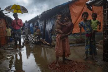 Two children holding younger children on a rainy day in the refugee camp