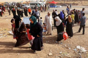 Refugees carrying baggage as they move toward safety in iraq.