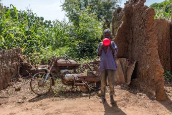 A boy blowing up a bright red balloon in nigeria