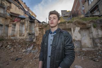 Sami, a teenage syrian refugee, pictured in front of buildings in turkey