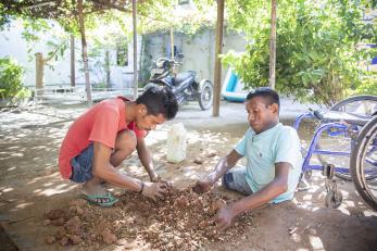 Freddie pictured with another man working to prepare mud to use in manufacturing the clean cookstoves