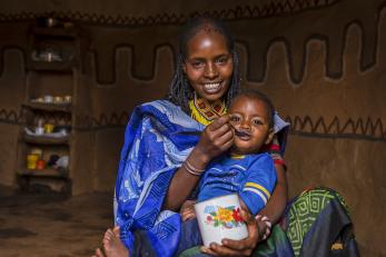 A woman feeding a toddler with a spoon in ethiopia