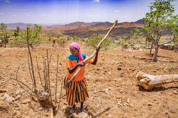 Manase pictured in a field holding a tool