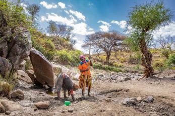 Two women dig in the sandy riverbed to access water during the dry season in ethiopia