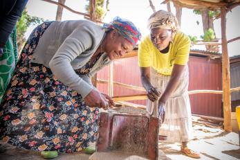 Two women leaning over a cookstove