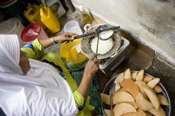 A woman cooking over a stove in indonesia