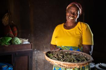 A woman in kenya holding a platter of pigeon peas