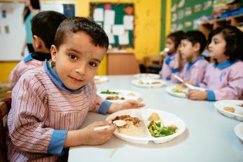 A boy in at lunch in lebanon pictured with a plate of food divided into compartments