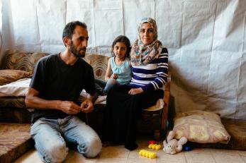 A husband and wife sit with their young daughter in lebanon