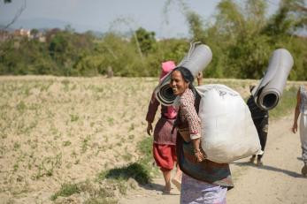 People carry disaster relief kits on a dirt road in nepal