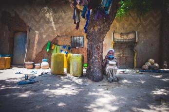 Person sitting beneath a tree eating from a bowl with a spoon