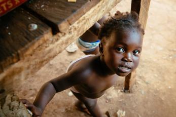 A curious toddler looking up from underneath a wooden table