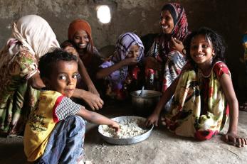 A family gathered around a platter of food in yemen