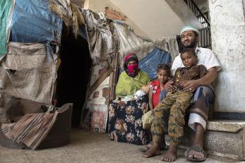 A man and woman sit with several of their children inside an abandoned school they are using as a shelter