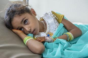 Nehan, a young girl, lying on her side in her hospital bed with her head resting on her hand