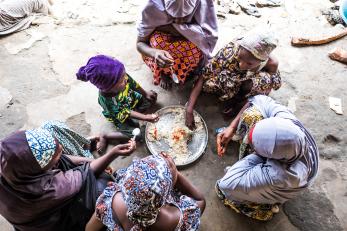 People gathered around a plate of food in nigeria