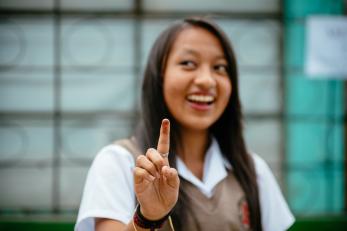 A girl smiling and holding up her raised index finger in guatemala