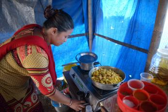 A woman cooks potatoes on a gas stovetop in nepal