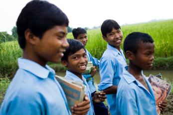 A group of students smile while walking home from school.