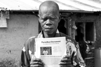 A person holds a document while standing in front of a building.