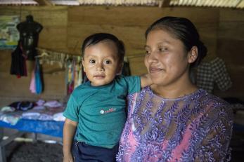 A mother holds their baby inside their home in guatemala.