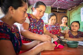 An adult counts money with a group of people at local savings and loan group in guatemala.