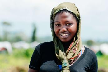 A person wearing a headscarf smiles for the camera.