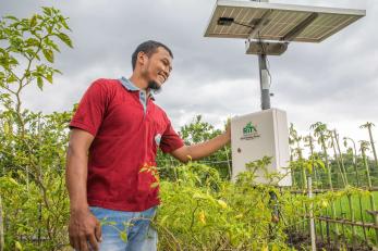 A farmer stands beside his soil and weather monitoring station.