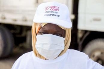 A person in  in lower juba province, somalia, wearing a face mask and hat with the words covid-19 response.