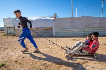 A child pulling kids on a broken cart. 