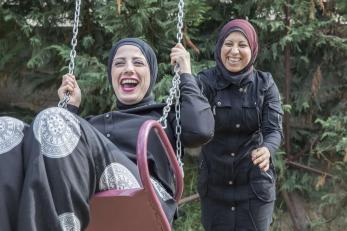 A person pushes their friend in a swing.