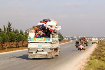 A family travels in the flatbed of a truck.  