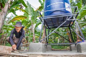 A mercy corps indonesia worker troweling concrete on a platform to support a water station in western java