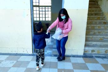 A child receives a bag of ppe from an adult.