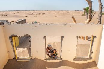 Hasan ali gafar afat and his son at the ruins of their former home, which was overtaken by desertification.