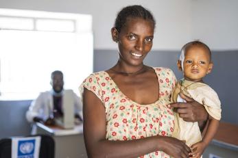 An adult holding child in a doctors office.