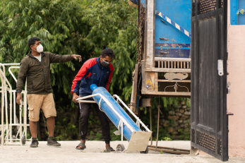 Two people deliver an oxygen tank.