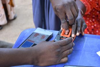 A mercy corps team member assists an e-voucher recipient with a digital identity process, increasing security and efficiency.